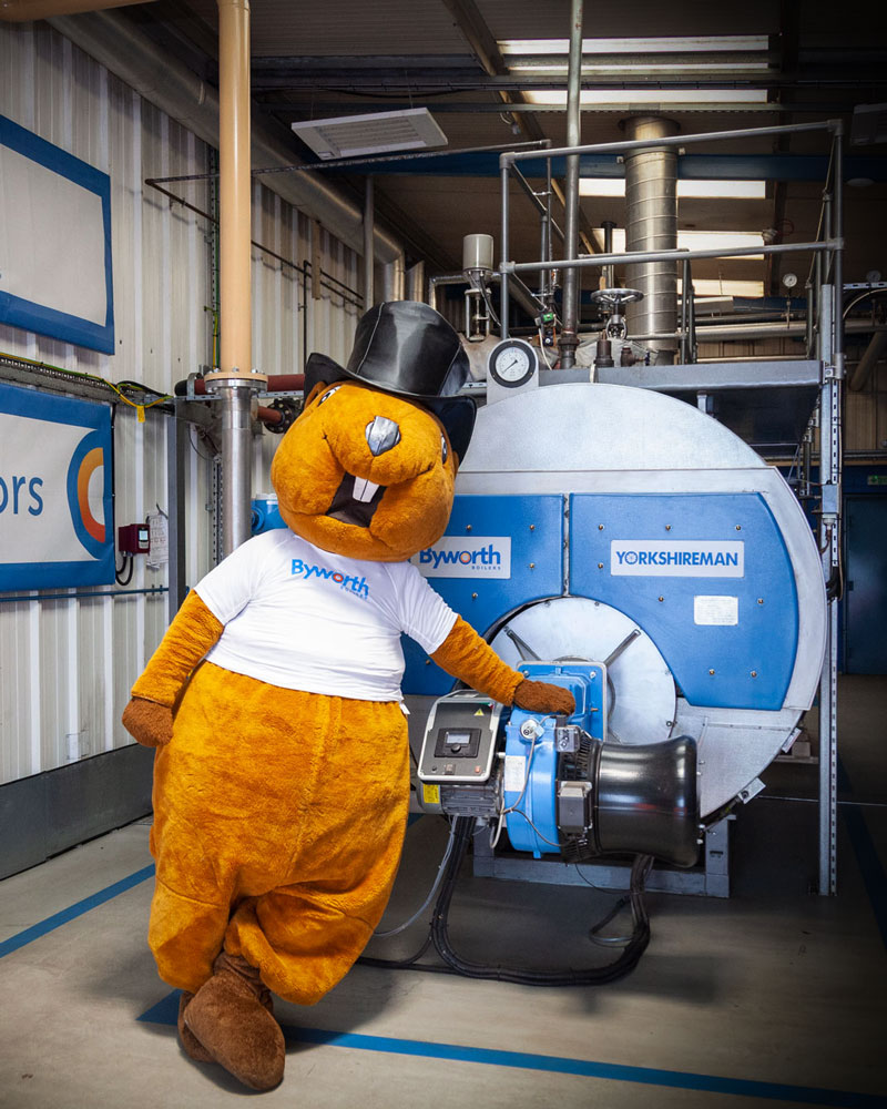 A man dressed in a mascot beaver costume stood by an industrial boiler